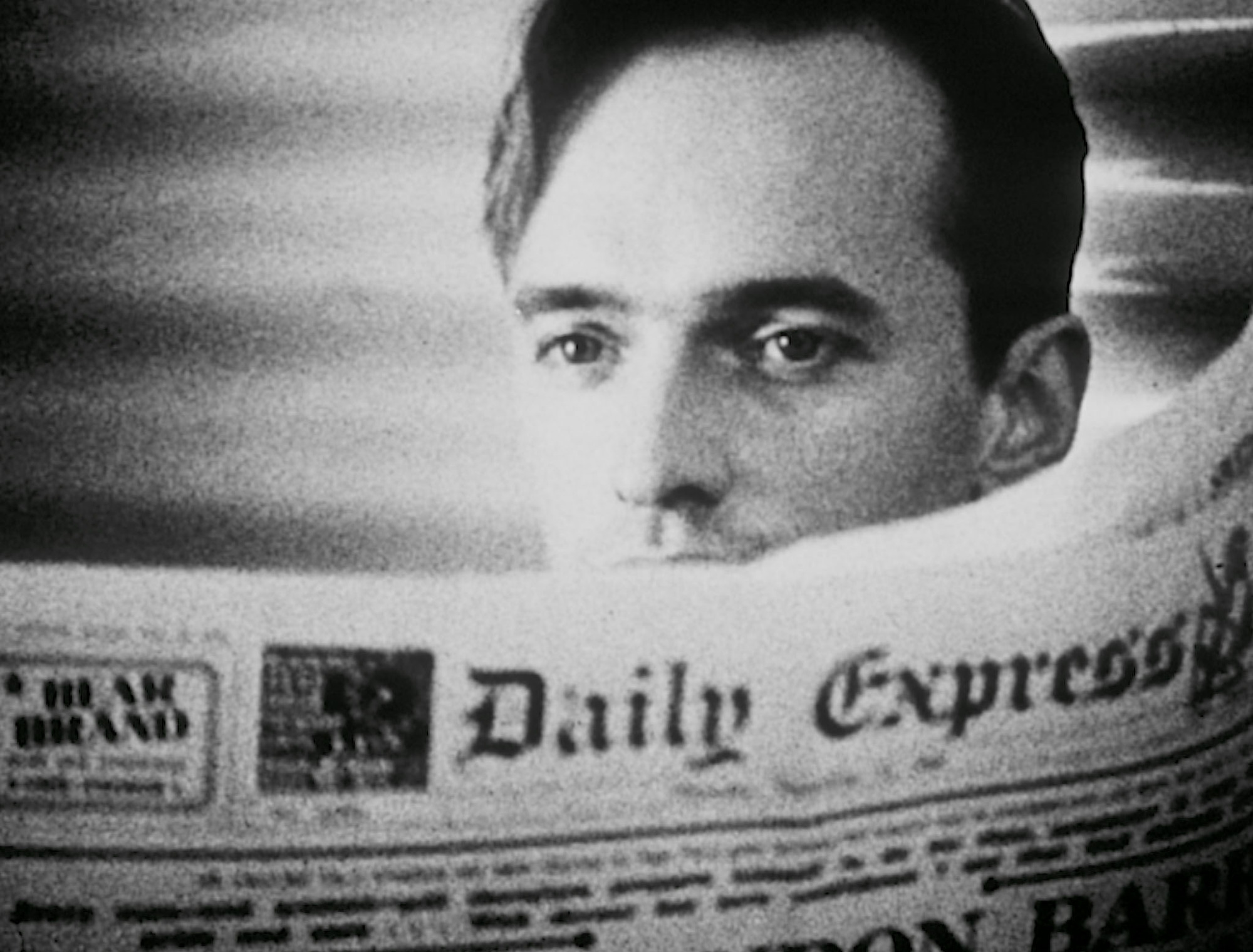 Black and white photo of a man peering over a newspaper