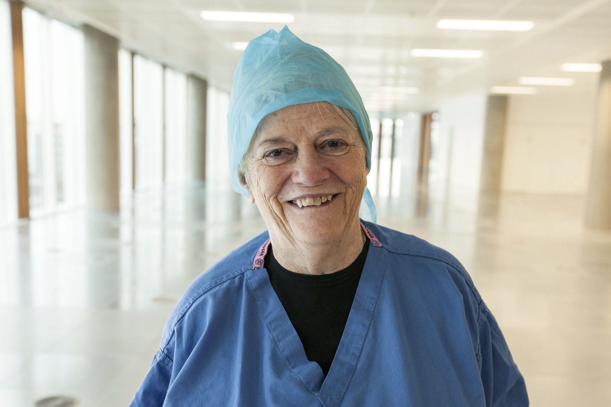 An old NHS female doctor smiles in a hospital hallway