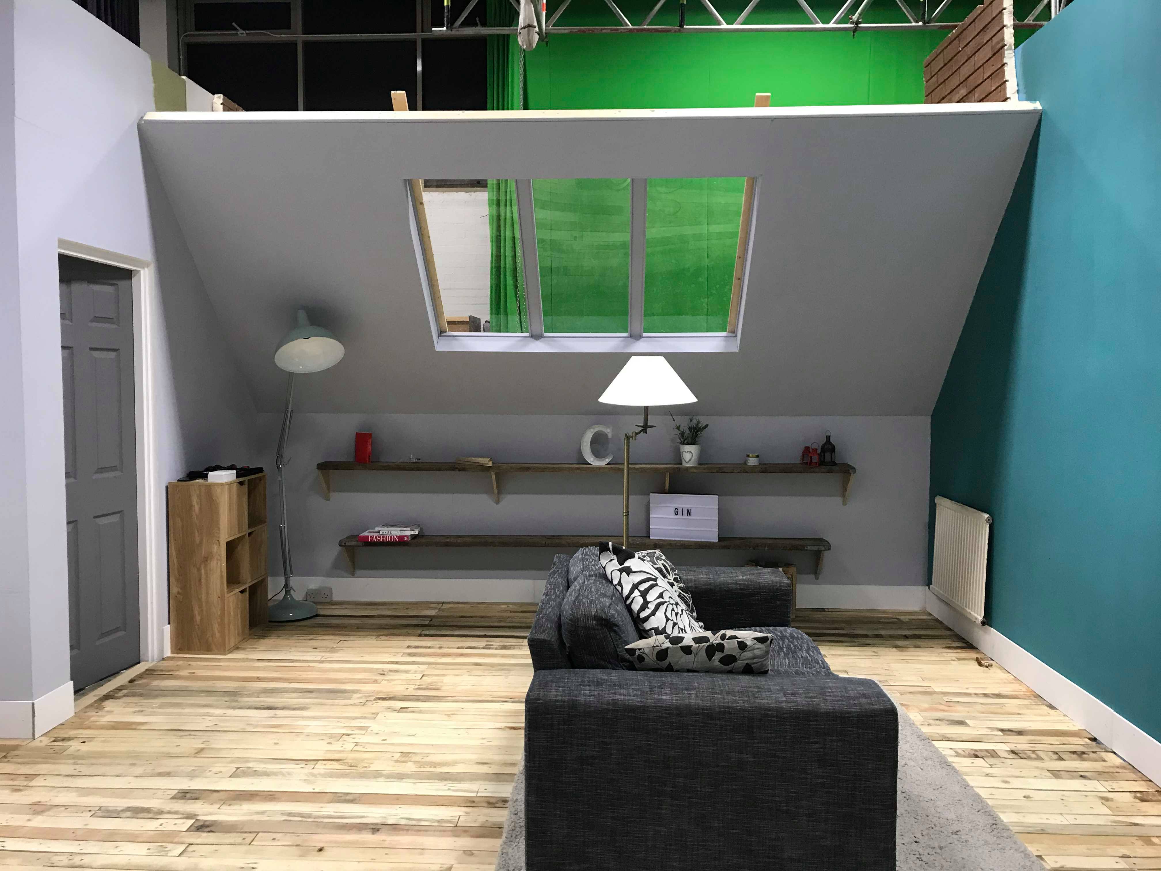 Interior set design of a living room with a sofa and shelves. Green screen in background.
